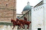 Vista di cavalli e cavalieri con sfondo campanile e abside del Duomo
