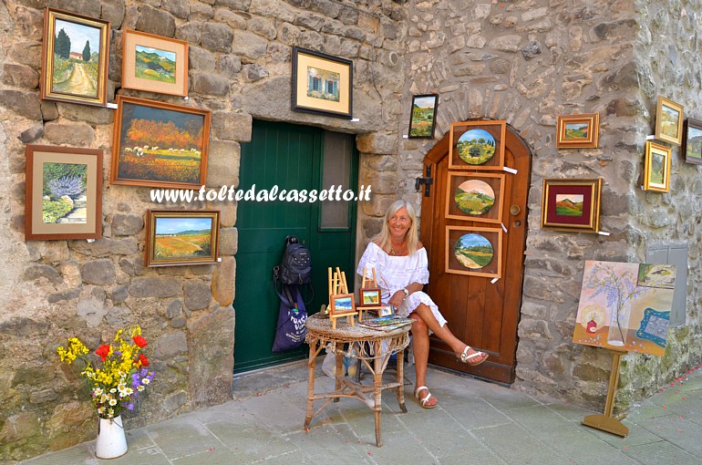 BRUGNATO (Infiorata del Corpus Domini 2019) - La pittrice brugnatese Anna Guani posa tra i suoi quadri bucolici esposti in Via dell'Olivo (Caruggettu)