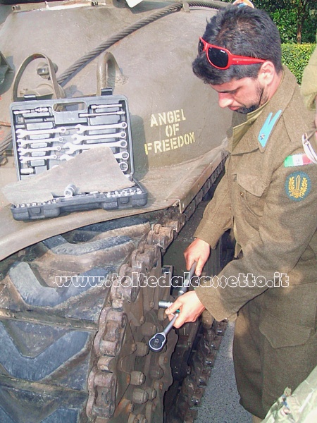 Un figurante in divisa addetto alla manutenzione dei cingoli di un carro armato M4 SHERMAN