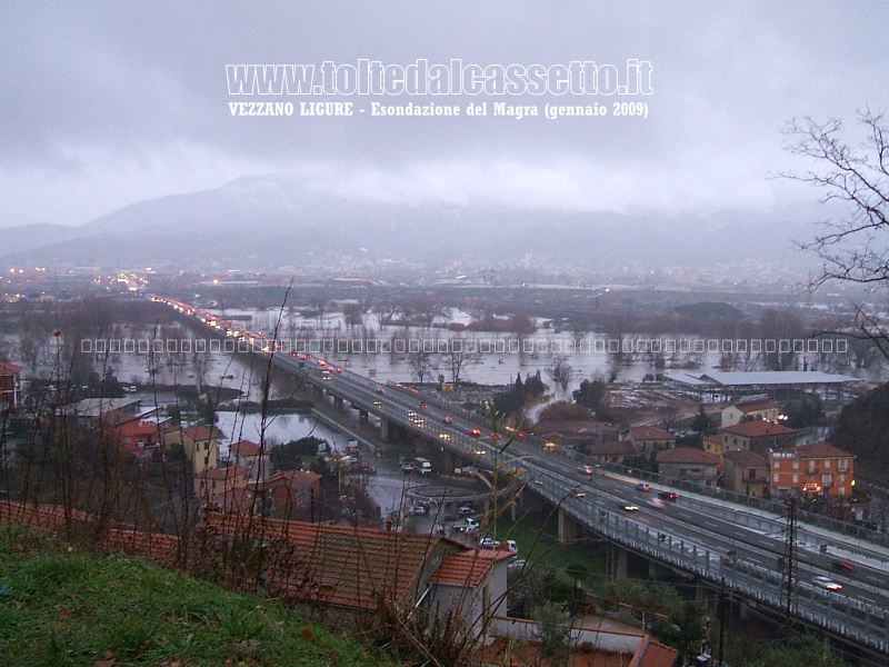 VEZZANO LIGURE (gennaio 2009) - E' sera, il cielo  plumbeo e scarica pioggia a dirotto. Il raccordo dell'Autostrada A15 Parma-La Spezia scorre sopra la campagna allagata dopo l'esondazione del fiume Magra