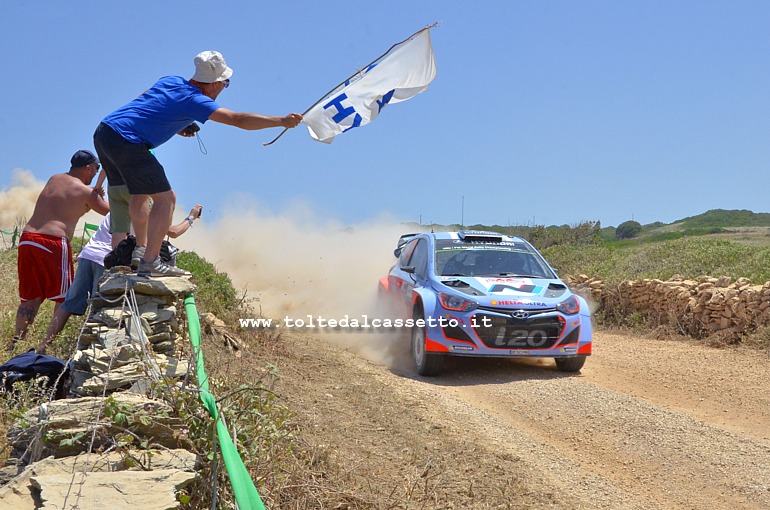 RALLY ITALIA SARDEGNA 2014 - Hayden Paddon (NZL) e John Kennard (NZL) su Hyundai i20 WRC (n.20) al loro passaggio vengono incitati da alcuni tifosi che sventolano una bandiera col logo del marchio automobilistico coreano