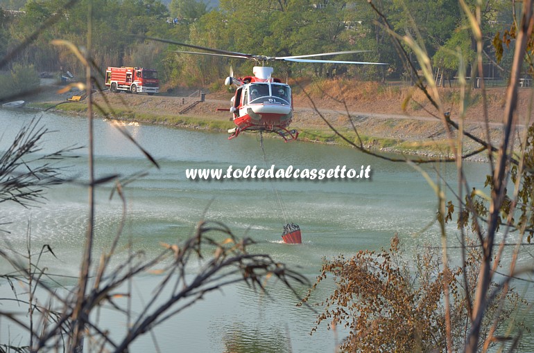 PARCO DEL MAGRA (Piano di Vezzano Ligure) - L'elicottero dei Vigili del Fuoco, intervenuto per spegnere gli ultimi focolai dell'incendio scoppiato il 7 agosto 2015, carica la benna nel Lago Curadi