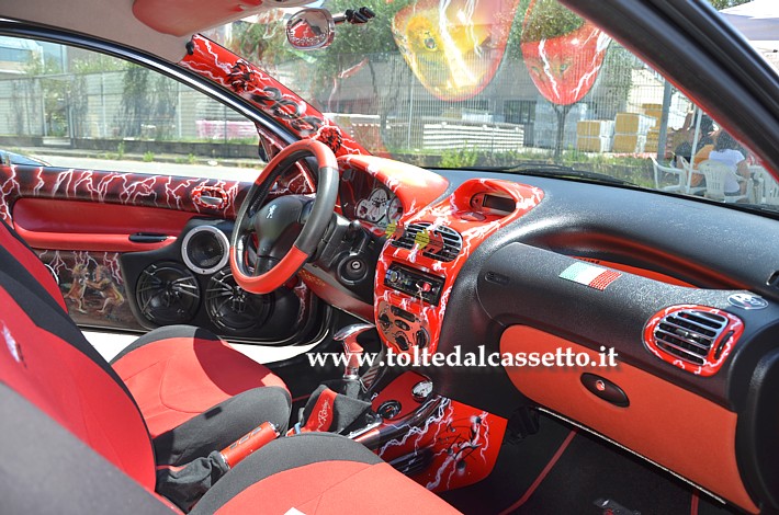 TUNING - Peugeot 206: interni di colore rosso e nero con decorazioni manuali, tra i quali alcuni disegni raffiguranti dei leoni
