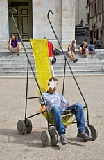 PIETRASANTA (Piazza Duomo) - Un "passeggino" gigante appartenente all'opera "Stallers" dell'artista giamaicano Nari Ward. Le sculture sono interattive ed i visitatori posso sedersi, come ha fatto questo turista