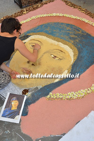 BRUGNATO (Infiorata del Corpus Domini 2015) - Un'infioratrice da vita ad un volto di Madonna contornato da fiori secchi e petali di margherita