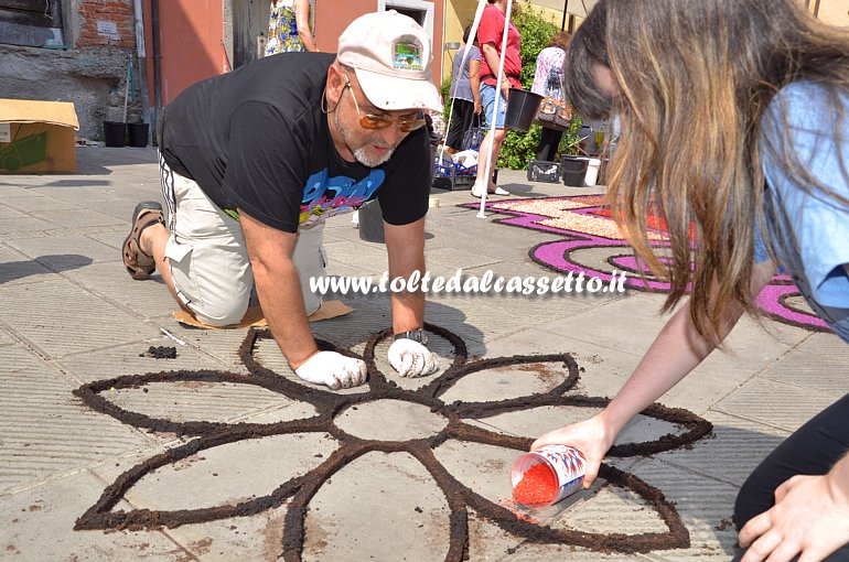 BRUGNATO (Infiorata del Corpus Domini 2015) - In Via Riva D'Armi due infioratori riempiono di sabbia colorata i petali di un fiore disegnato con fondi di caff