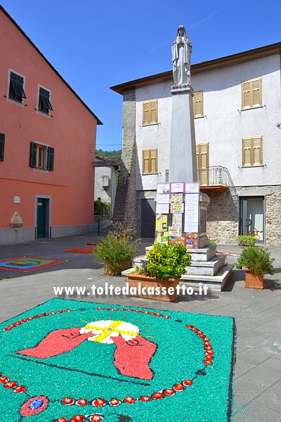 BRUGNATO (Infiorata del Corpus Domini 2018) - In Piazza De Gasperi (Piazza della Madonna) erano allestiti i disegni delle scuole locali tra i quali questo raffigurante delle mani che sorreggono un'ostia