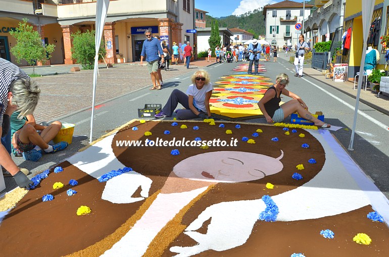 BRUGNATO (Infiorata del Corpus Domini 2018) - Allestimento di un quadro con mani stilizzate che avvolgono un mantello su volto di Madonna