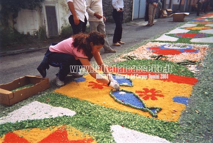 BRUGNATO (Infiorata del Corpus Domini 2004) - In Piazza Ildebrando un'infioratrice compone un disegno raffigurante pesci e petali di fiori