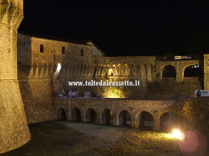 SARZANA - I visitatori della Fortezza della Cittadella, ripresi col tempo lungo della foto notturna, sembrano muoversi come fantami sul ponte del maniero