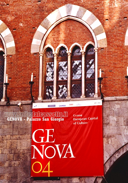 GENOVA - Una finestra dell'avancorpo medievale di Palazzo San Giorgio espone un drappo col logo di "Genova 2004 - Capitale Europea della Cultura"