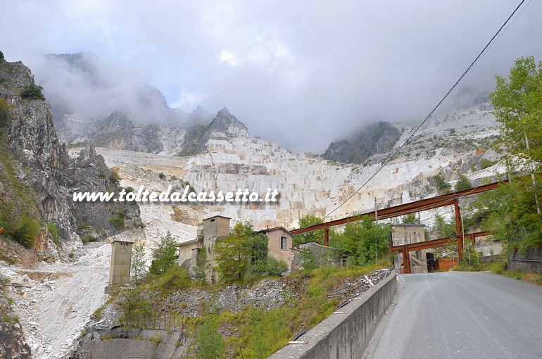 TORANO - La spettacolare cava n. 44 - Buca di Ravaccione. Le montagne soprastanti sono avvolte dalle nuvole; in basso si vedono gli antichi fabbricati al servizio dei cavatori, oggi dismessi