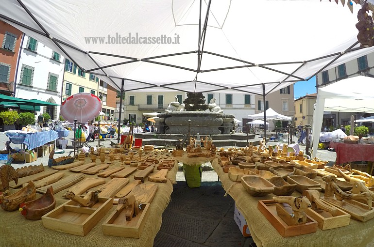 FIVIZZANO - Oggetti d'artigianato in legno di fronte alla fontana della Piazza Medicea durante la manifestazione "Mercante per un giorno"