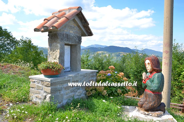 CROCETTA DI MULAZZO - "Donna che prega in ginocchio" di fronte ad un'edicola votiva, scultura in legno del maestro d'ascia Gino Fogola