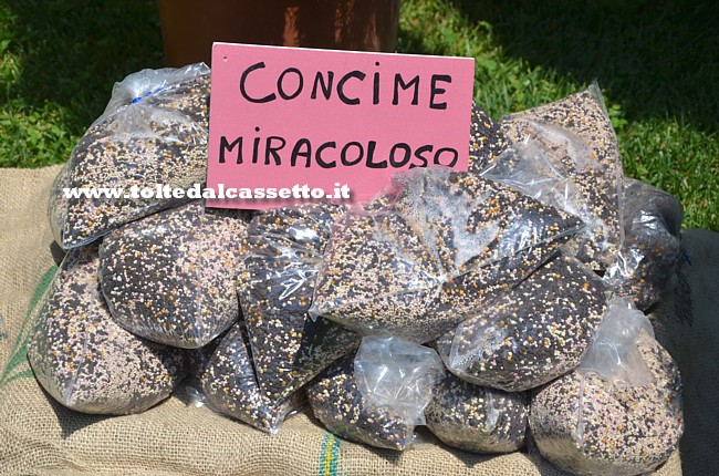 CARTELLI CURIOSI E DIVERTENTI - Sacchetti di "concime miracoloso" in esposizione durante una fiera agro-alimentare