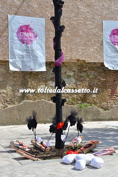 CIBART 2016 (Seravezza) - Albero cittadino fasciato con la tecnica dell'"Urban Knitting". Dietro si intravedono due manifesti col logo della manifestazione 
