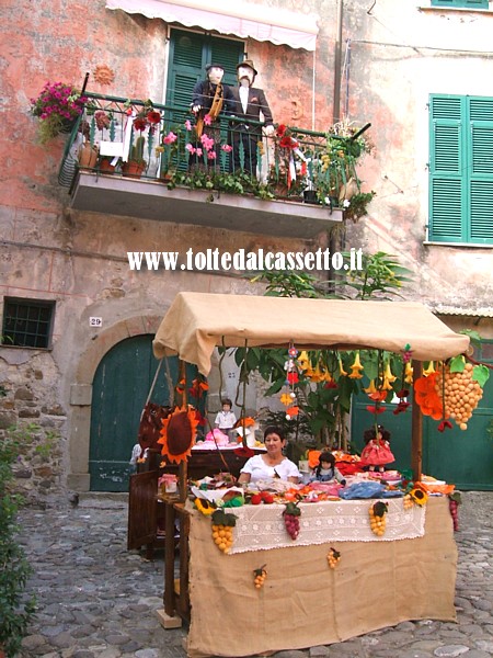 VEZZANO LIGURE (Sagra dell'Uva) - Pupazzi in stoffa affacciati ad un balcone e una bancarella di prodotti artigianali nel borgo soprano