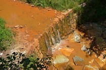 VALDICASTELLO CARDUCCI - Il letto del torrente Baccatoio colorato di rosso per i sedimenti ferrosi che vengono trascinati a valle dalle miniere di pirite abbandonate e mai bonificate