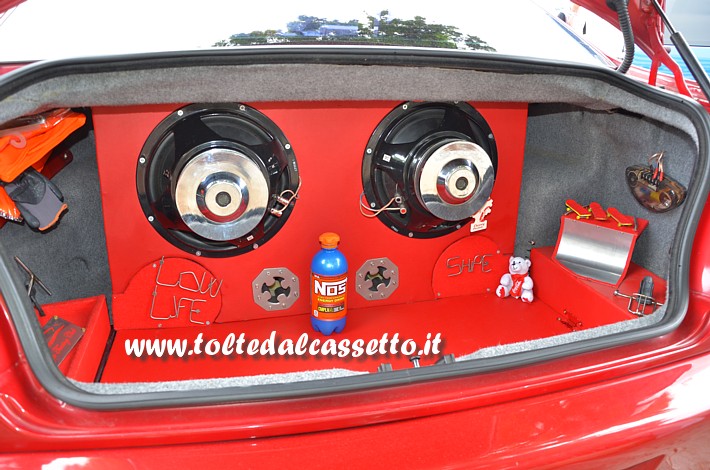 TUNING - Bagagliaio in tinta rossa di BMW Serie 3 con due subwoofer e oggetti vari