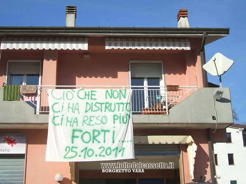 BORGHETTO VARA - Dal balcone di una casa danneggiata scende un drappo recante una scritta che testimonia la forza della popolazione