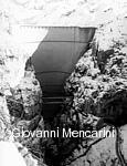 Il fronte della diga del Vajont in una foto moderna. Come si può vedere, l'opera non venne minimamente scalfita dall'enorme impatto di terra e roccia staccatesi dal monte Toc.